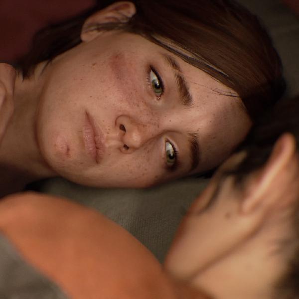 Ellie lies down close to someone whose face we can see, looking intimately at them, her face slightly bruised and sad